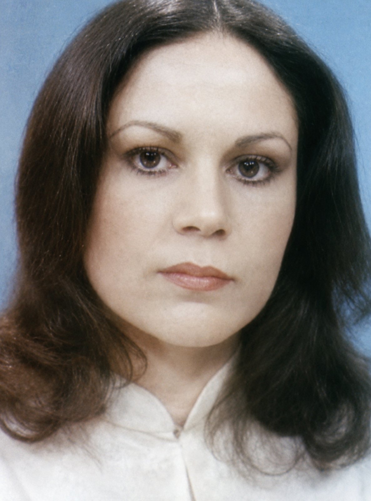 Parissa in a cream high-collared blouse against a blue studio backdrop — portrait from the NIRT / formative years